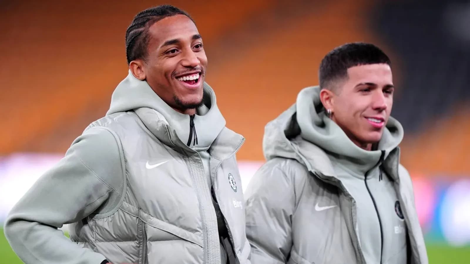 Two players smiling in training jackets on field Two players smiling in training jackets on field