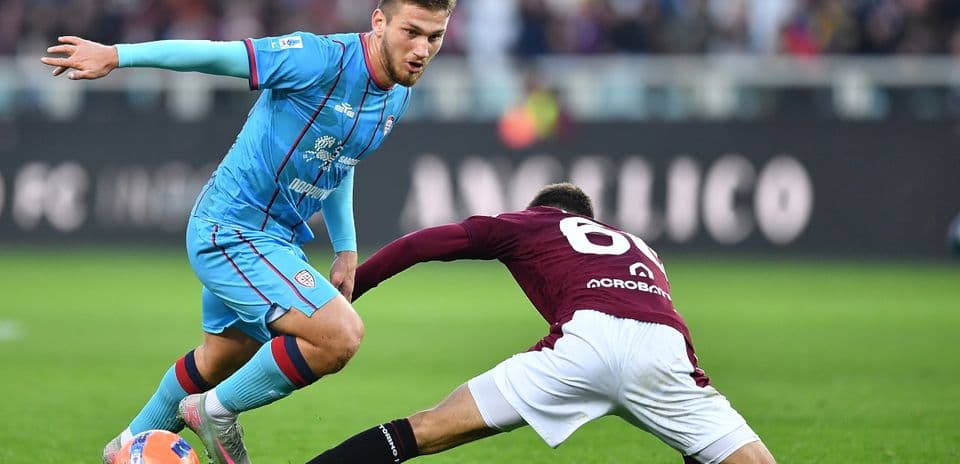 Cagliari player evading tackle during Serie A match Cagliari player evading tackle during Serie A match