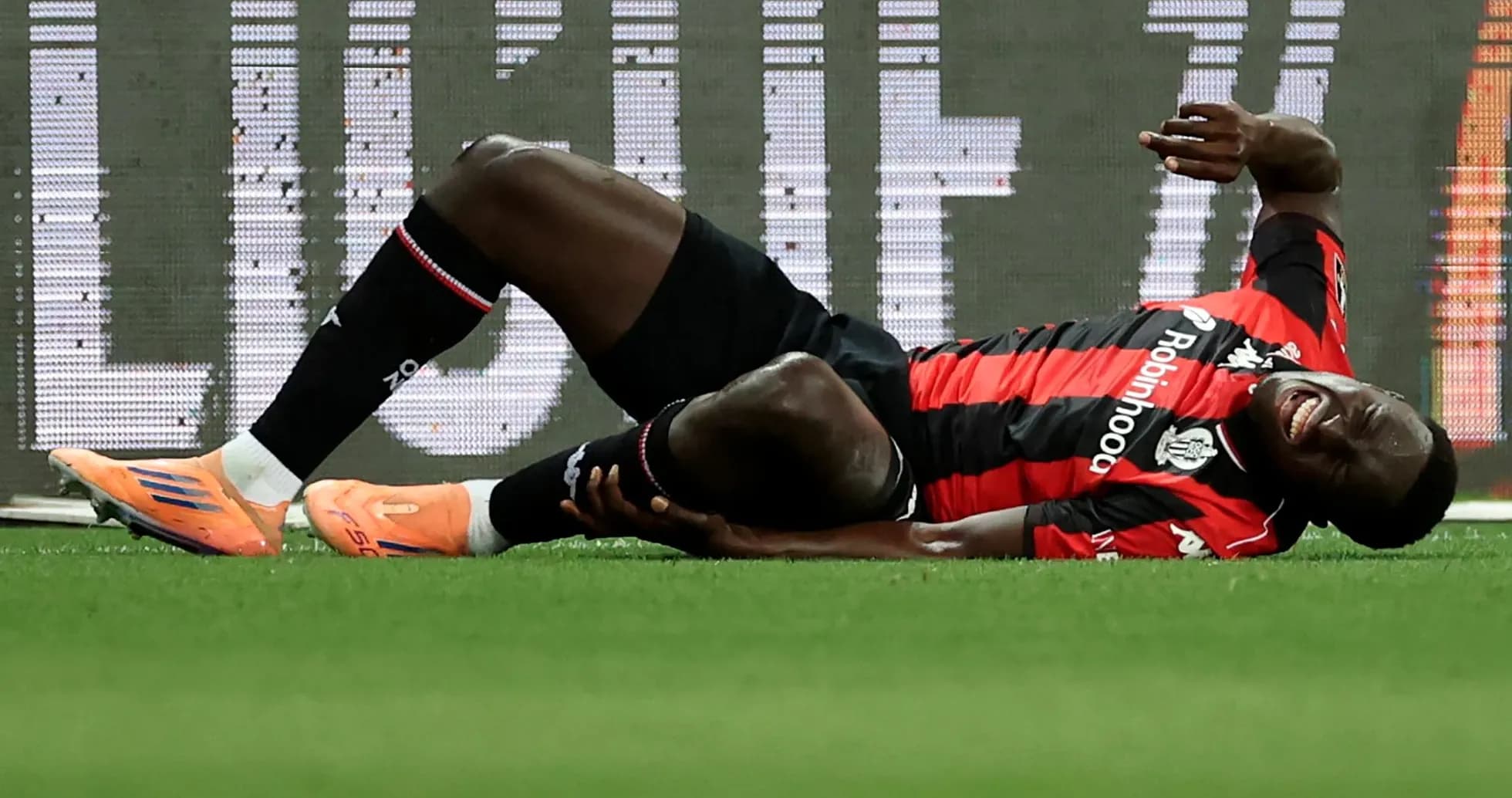 Player lying on ground, holding injured leg Player lying on ground, holding injured leg