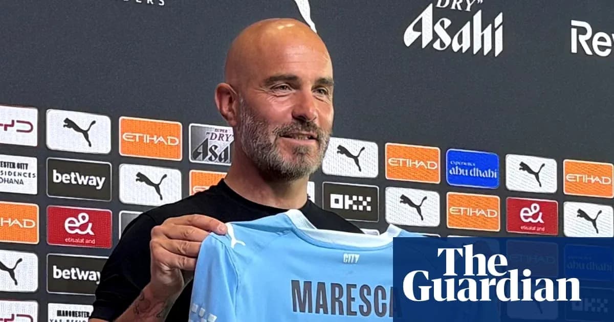 Manager holding a Manchester City jersey at press conference Manager holding a Manchester City jersey at press conference