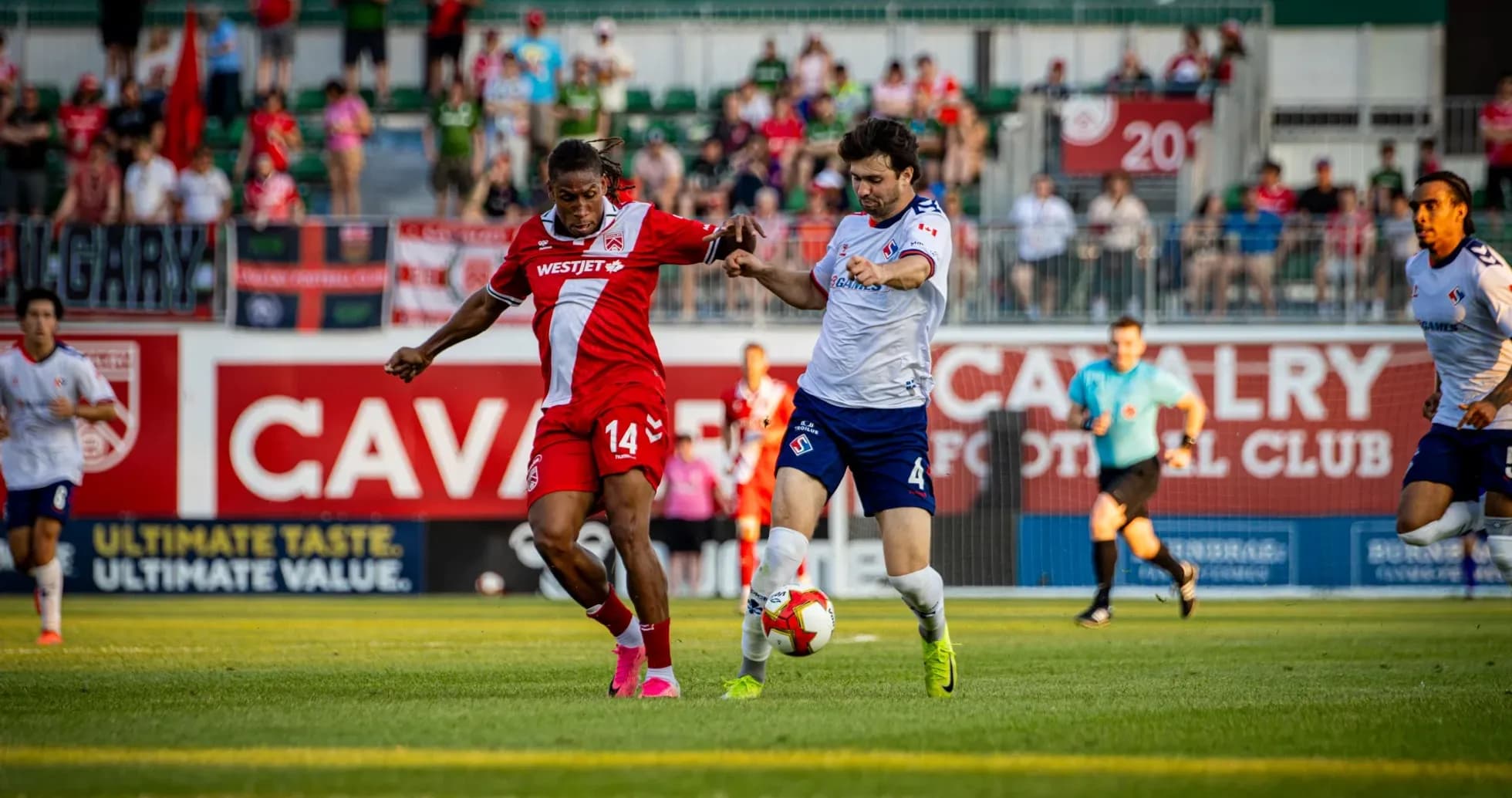 Cavalry FC player tackling Supra du Quebec opponent Cavalry FC player tackling Supra du Quebec opponent