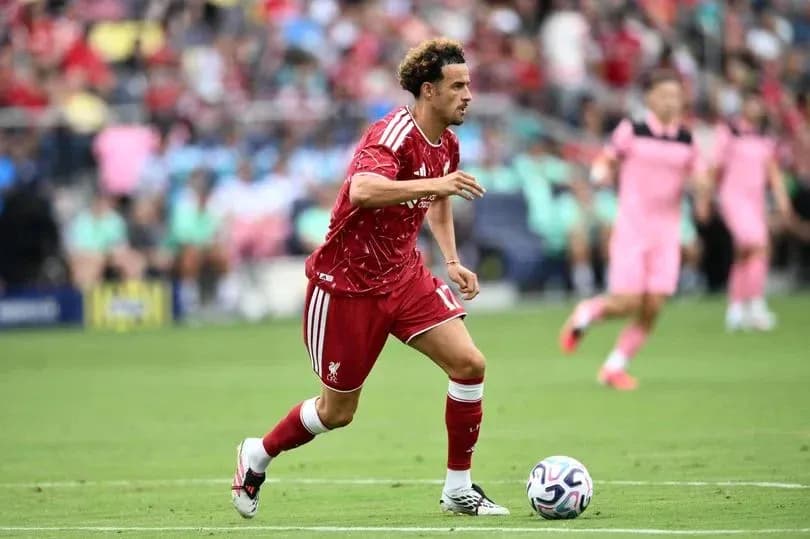 Player in red jersey dribbling ball on field Player in red jersey dribbling ball on field